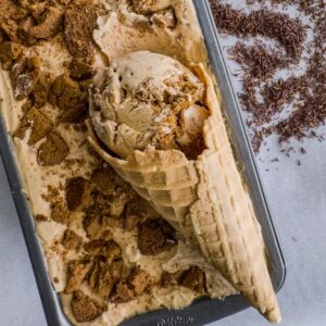 Rooibos and gingersnap ice cream in a loaf pan with a scoop of ice cream in a cone