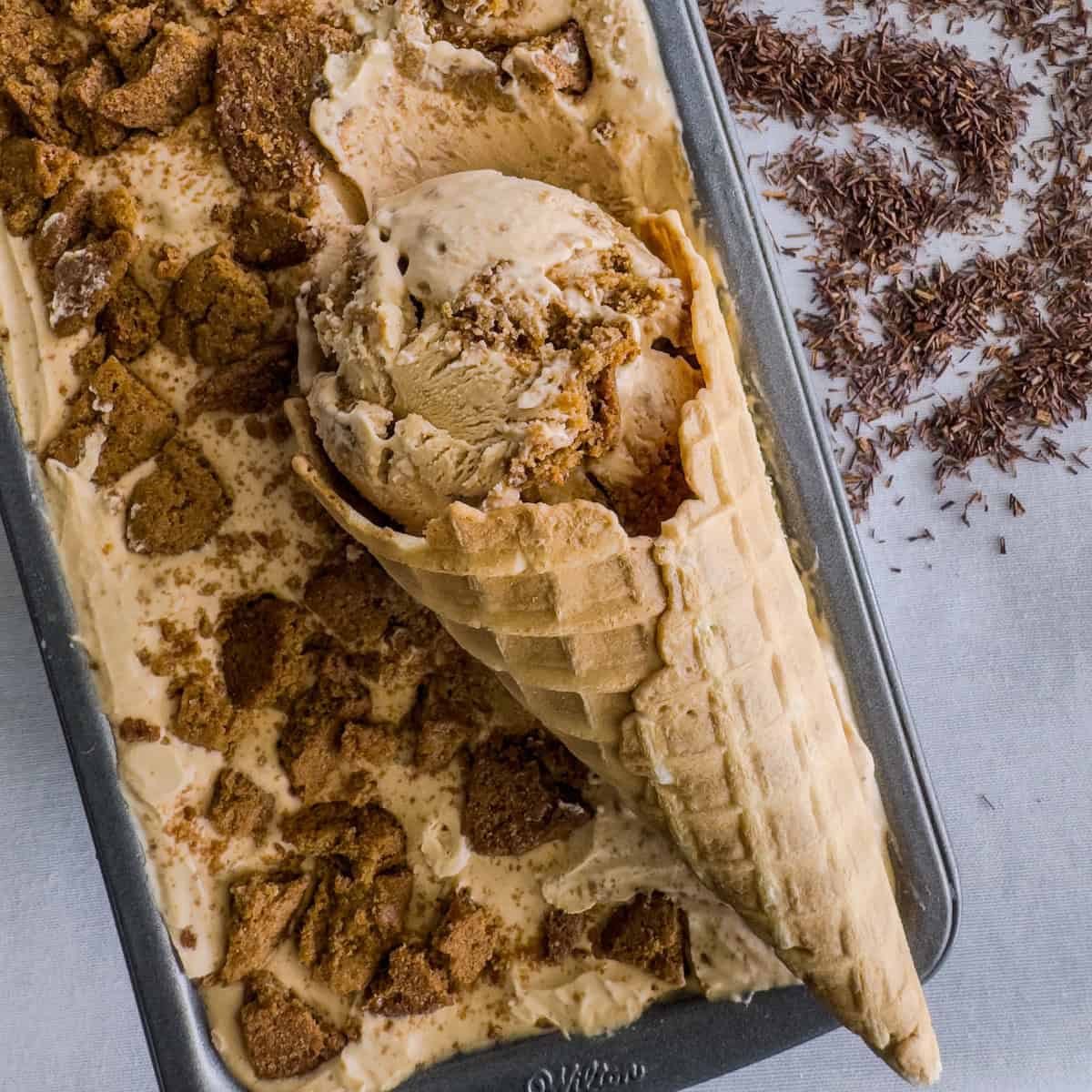 No-churn rooibos and gingersnap ice cream in a loaf pan with a scoop of ice cream in a cone