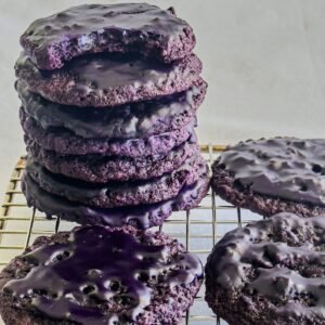 Iced Ube Oatmeal cookies piled on a cooling rack