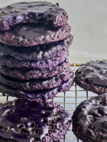 Iced Ube Oatmeal cookies piled on a cooling rack