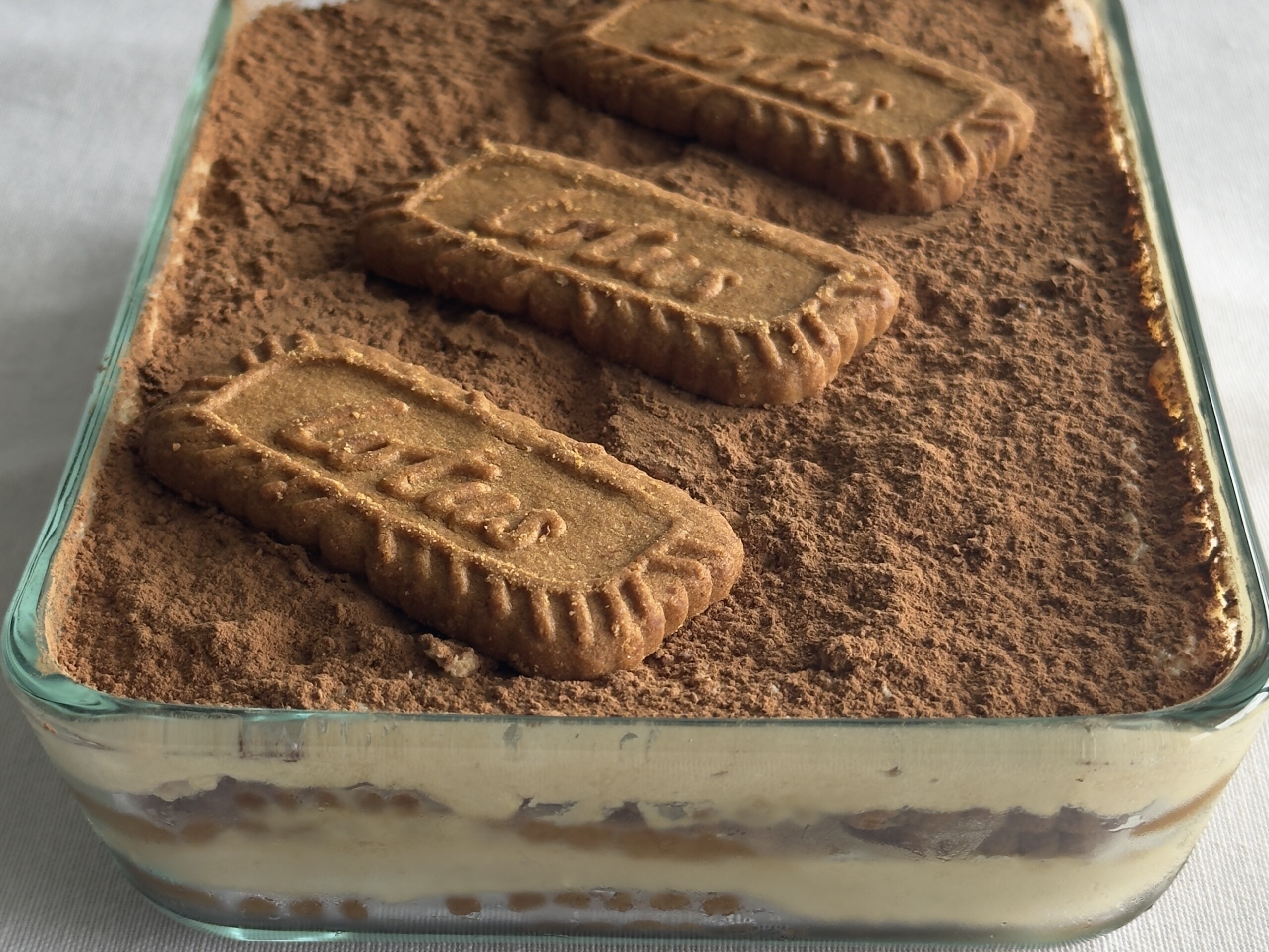 Fully assembled speculoos tiramisu, showing layers and toppings of cocoa powder and cookies