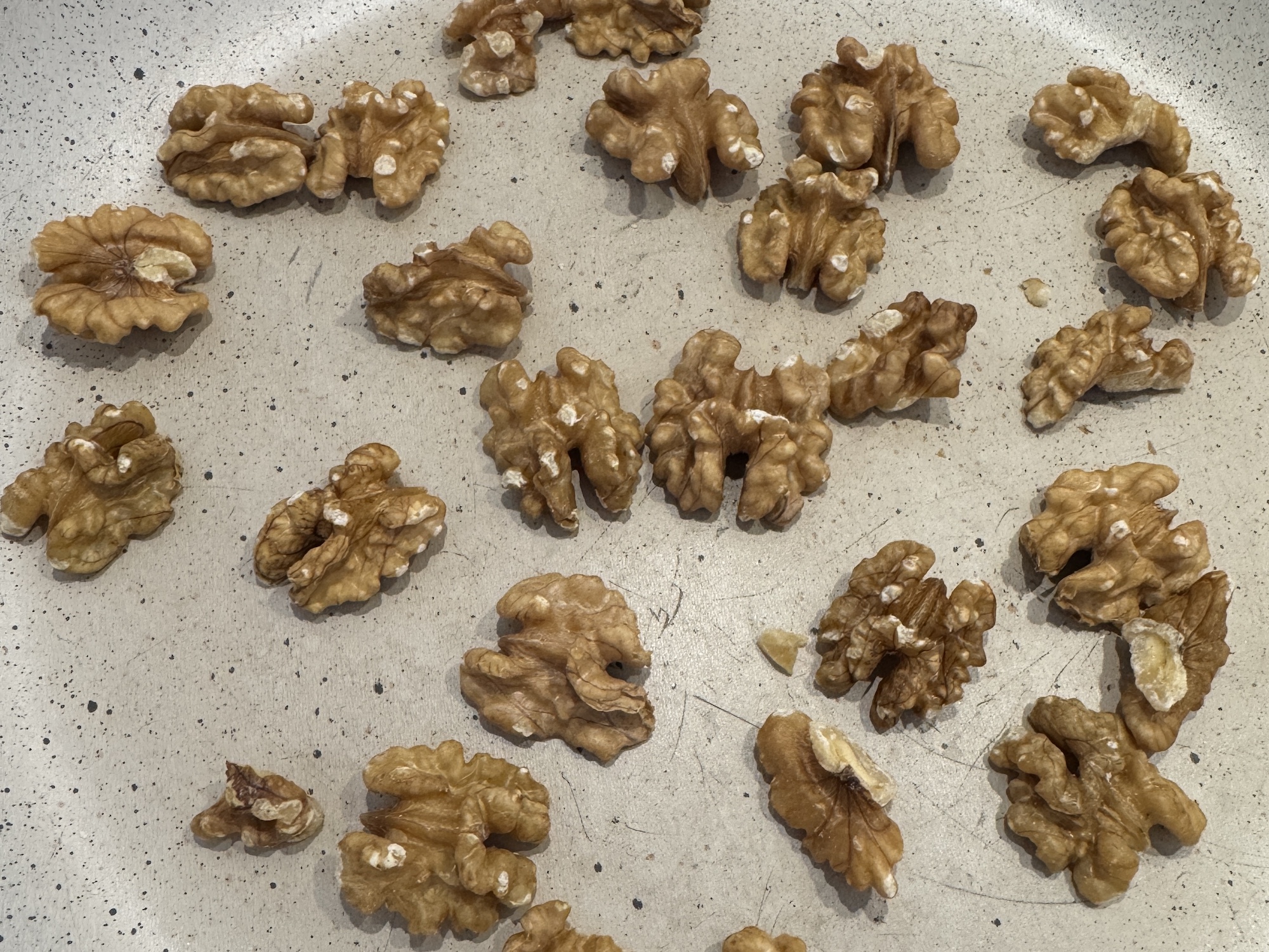 Whole walnuts toasting in a skillet in a single layer