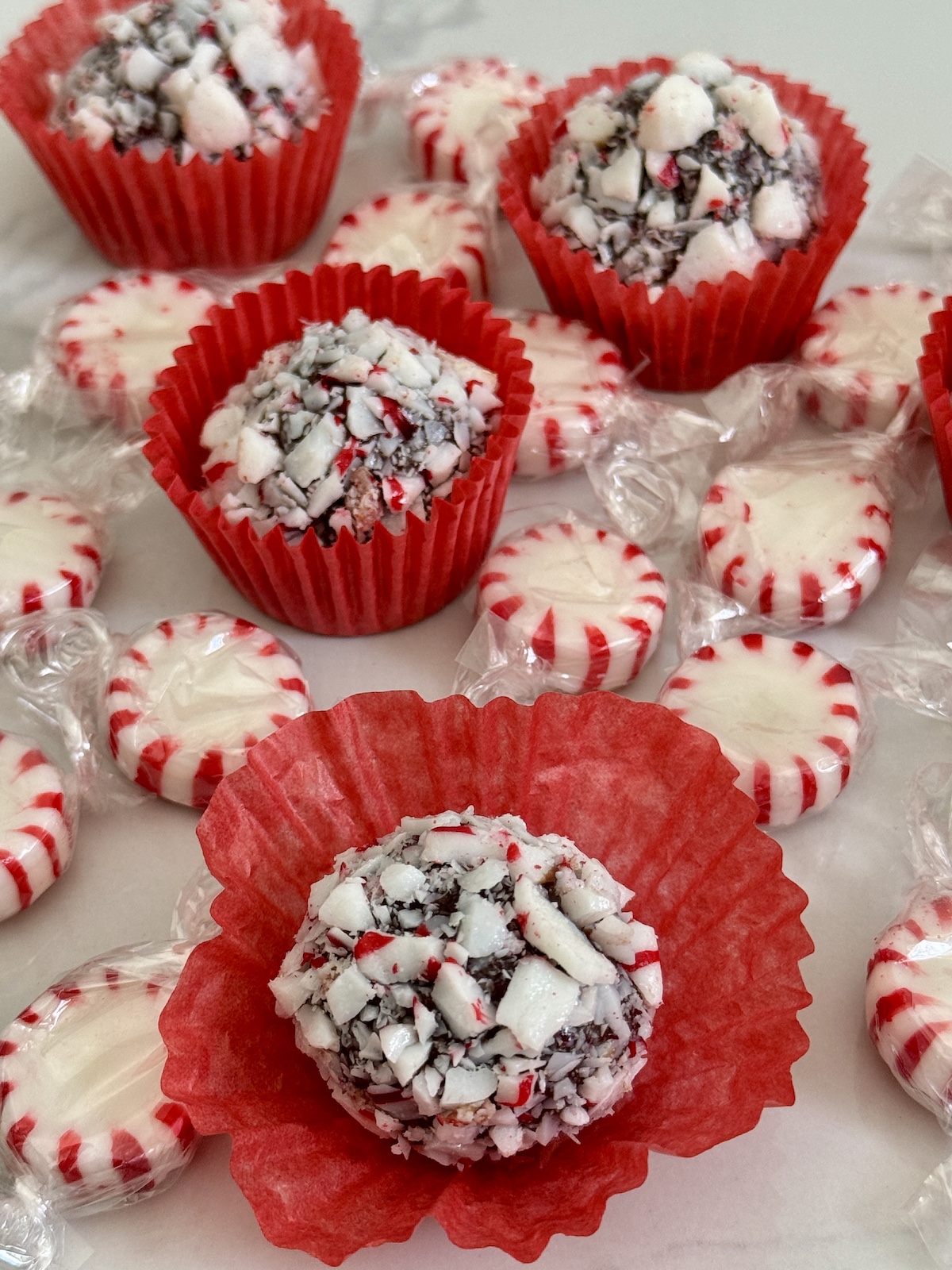 Peppermint fudge on red paper cups surrounded by peppermint candy