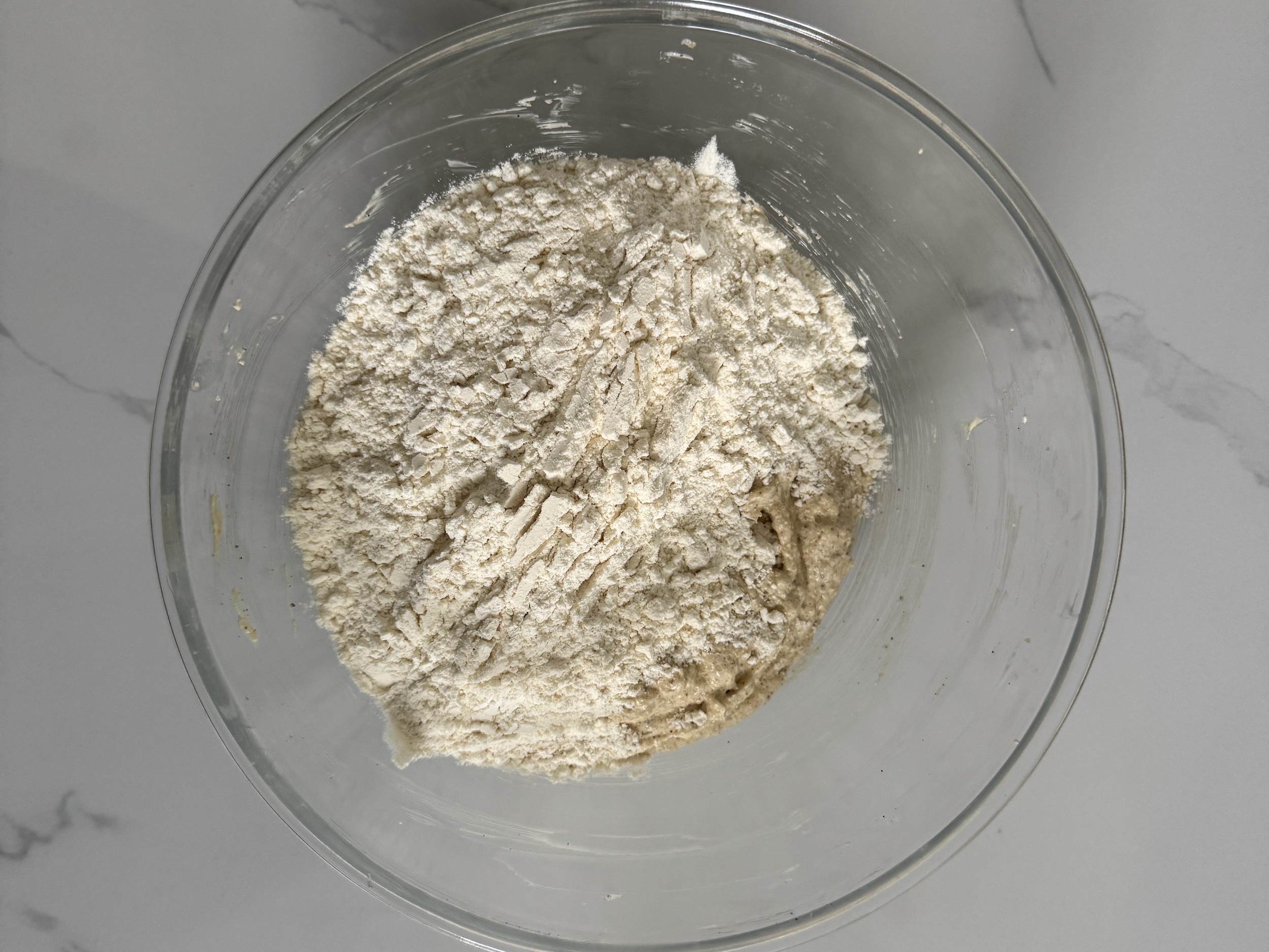 Dry ingredients added to the wet ingredients in the glass bowl