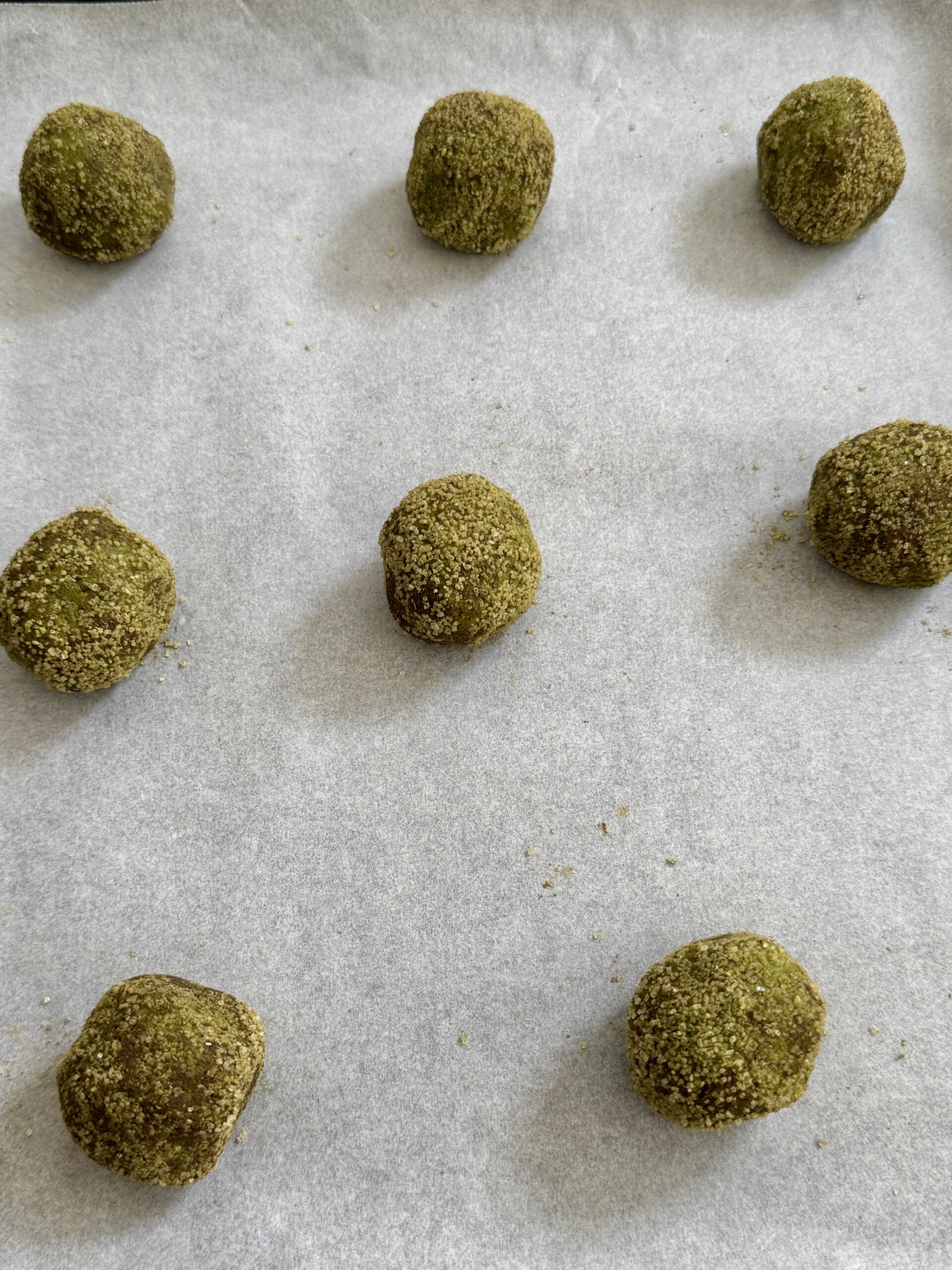 Matcha snickerdoodle cookie dough balls on baking sheet lined with parchment paper