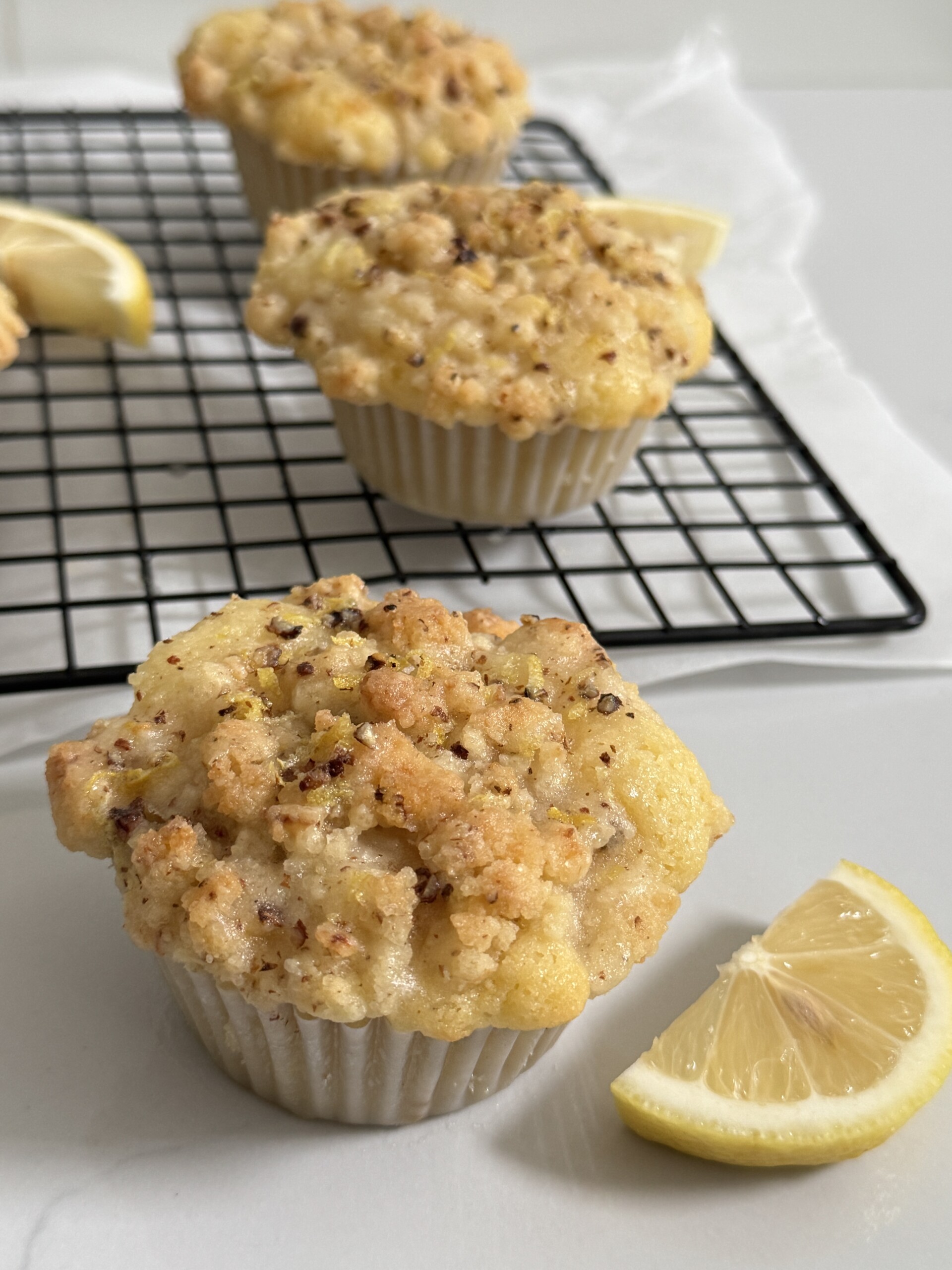 Lemon muffins on and near cooling rack with lemon slice